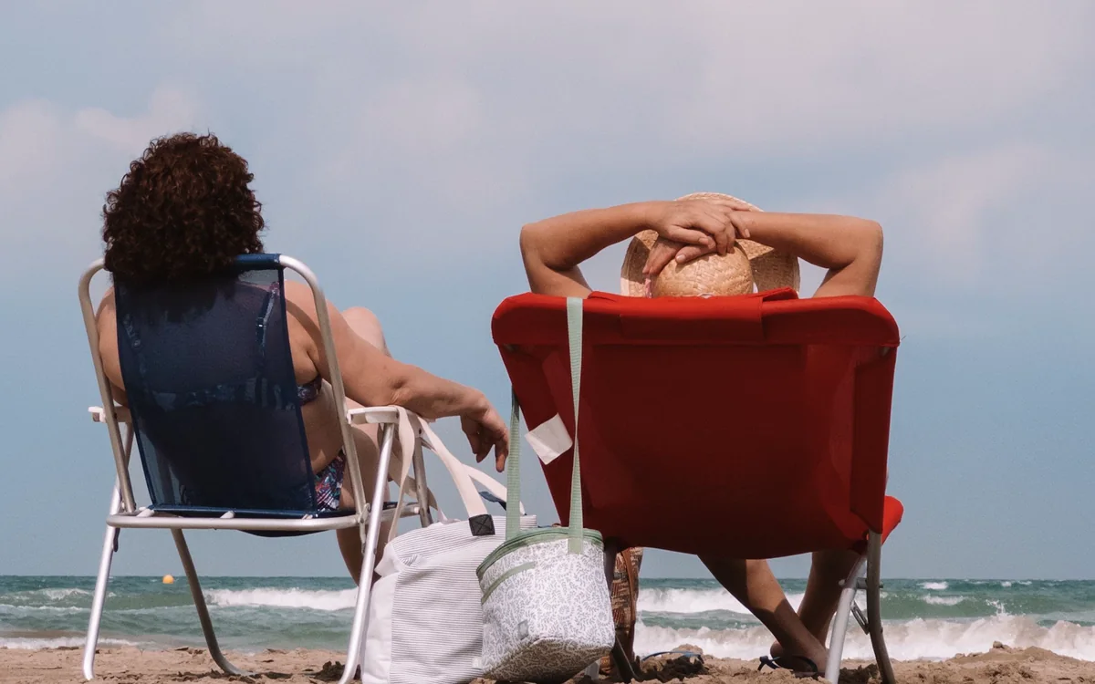 Huéspedes de vacaciones en tumbonas junto al mar y villa vacacional en Moraira